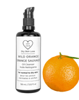 Miron violet glass bottle of orange face cleanser displayed with a fresh orange on a white background, Dry Skin Love Wild Orange Oil Cleanser for Dry Skin.